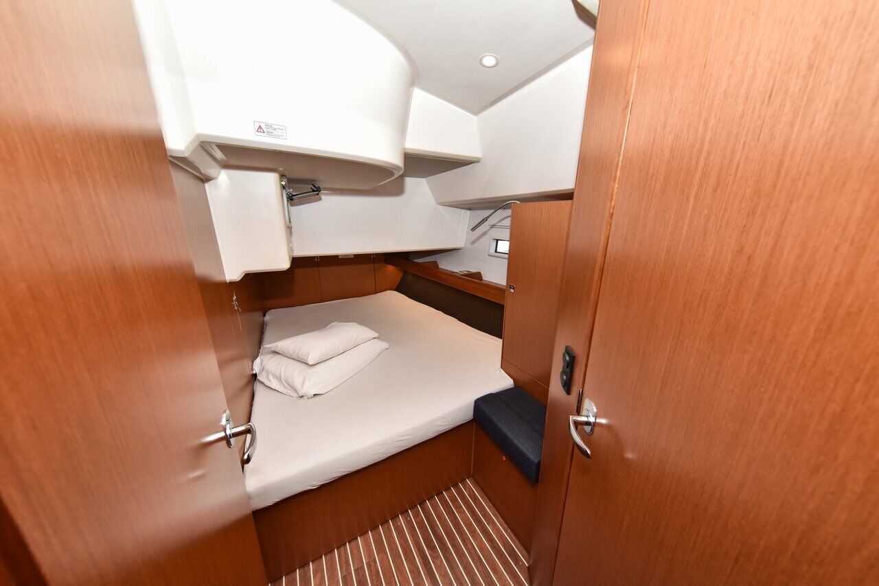 Een knus vakantiehuisje met een bed, een klein plankje en een raam.