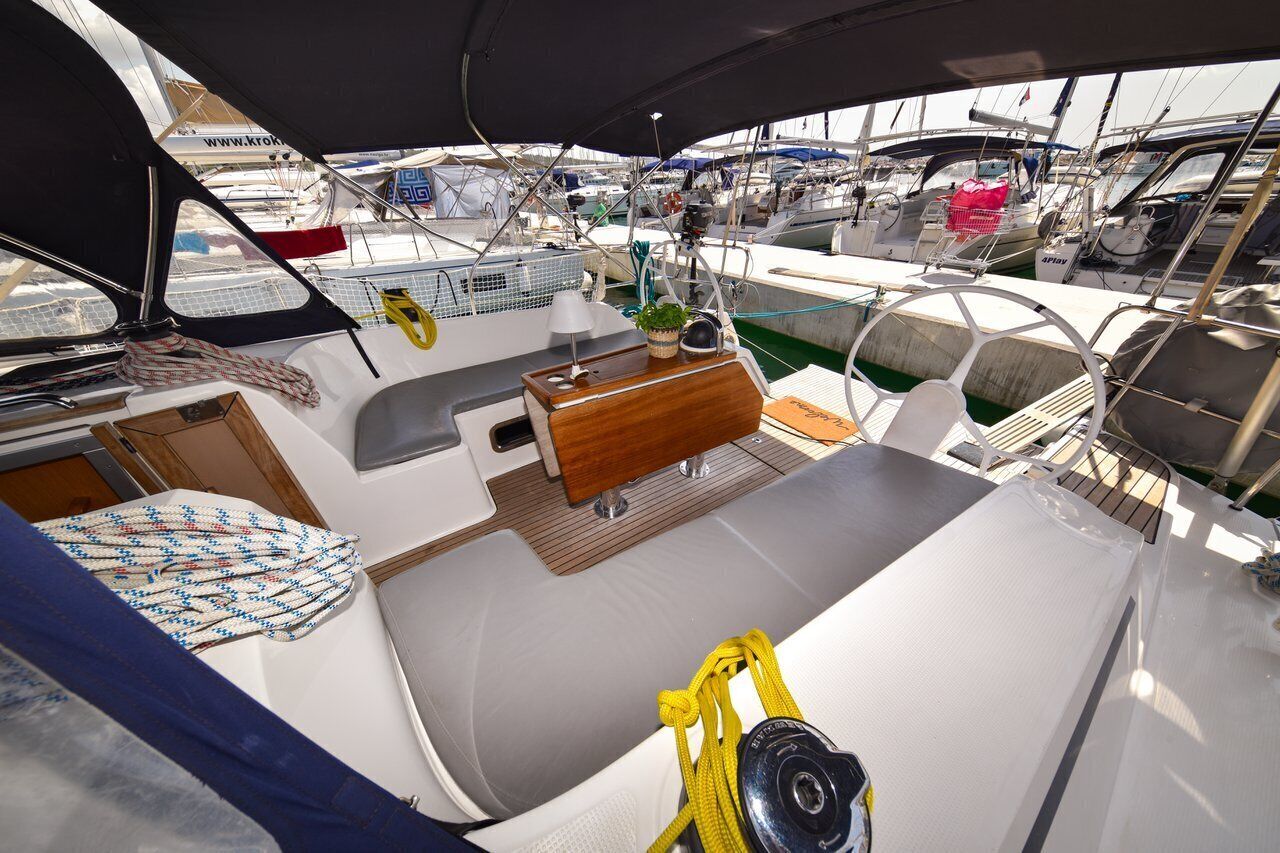 A boat deck with a dining area, a small table with a plant, and a yellow rope.