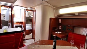 Un espacio interior funcional con una mesa de comedor, sillas tapizadas en rojo, una botella de vino y una pequeña zona de cocina.