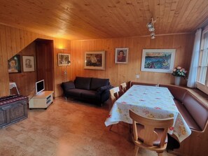 A wooden interior with a sofa, a table with floral tablecloth, and framed artwork on the walls. - Bachhüsi Appartement/Fewo, Dusche oder Bad, WC 6-Bettwohnung by Interhome (Zweisimmen)