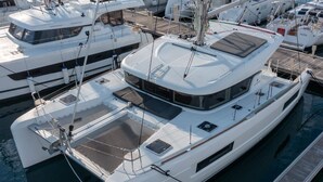 A white yacht docked at a marina with a covered deck area, multiple windows, and a name 'Q-YACHT' on the bow. - Sun-Kissed Sailing Adventure in Sibenik, Croatia (Primošten)