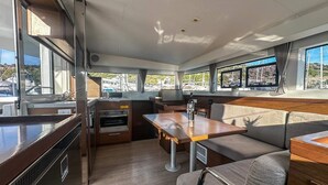 A compact kitchen with a built-in oven, a dining area with a table and bench, and large windows offering views of the marina. - Sun-Kissed Sailing Adventure in Sibenik, Croatia (Primošten)