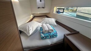 A compact cabin with a bed, pillows, a window with a view, and a small skylight. - Sun-Kissed Sailing Adventure in Sibenik, Croatia (Primošten)