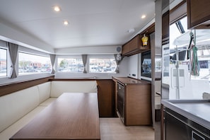 A compact galley with a wooden table, built-in seating, and a small kitchen area. - Sun-Kissed Sailing Adventure in the Ionian Islands, Lefkada (Lefkada)