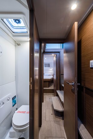 A narrow, modern bathroom with a skylight, a toilet, and a bench. - Sun-Kissed Sailing Adventure in the Ionian Islands, Lefkada (Lefkada)