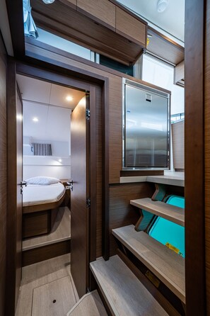 A compact, modern interior with a bed, built-in storage, and a refrigerator. - Sun-Kissed Sailing Adventure in the Ionian Islands, Lefkada (Lefkada)