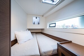 Ein kleines Zimmer mit einem Bett, einem kleinen Fenster und Blick nach draußen.