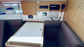 A compact boat interior with a dining area, control panel, and storage. - Sun-Kissed Sailing Adventure in Northern Croatia (Novi Vinodolski)