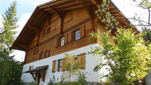 A traditional wooden chalet with a sloped roof, multiple windows, and a white lower section. - Zapfe (Küenzi) Appartement/Fewo, Dusche oder Bad, WC 6-Bettwohnung by Interhome (Gstaad)