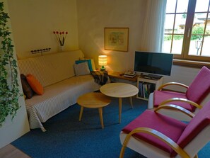 A cozy living room with a sofa, a small round table, a TV, and a bookshelf. - Zapfe (Küenzi) Appartement/Fewo, Dusche oder Bad, WC 6-Bettwohnung by Interhome (Gstaad)