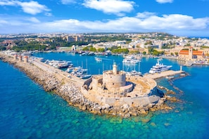 A coastal town with a historic fort, clear blue waters, and a marina with boats.