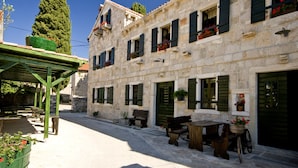 A stone building with multiple windows, a covered outdoor seating area, and a bicycle parked outside. - Sun-Kissed Sailing Adventure in Zadar, Croatia (Bibinje)