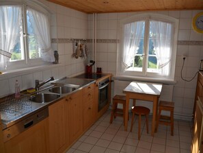 A kitchen with wooden cabinets, a sink, a stove, and two windows with curtains.