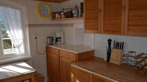 Una cucina con mobili in legno, una macchina da caffè e una sveglia appesa al muro.