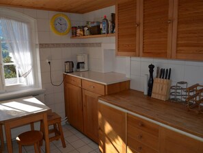 Eine Küche mit Holzschränken, einer Kaffeemaschine und einer Wanduhr.