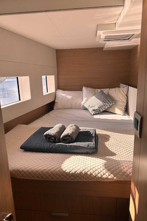 Ein gemütliches Blockhaus-Interieur mit einem Bett, Kissen, einer gesteppten Matratze und einem Fenster.