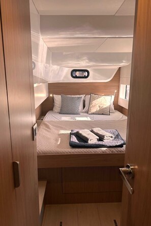 Ein gemütlicher, gut beleuchteter Raum mit Bett, Kissen und einem kleinen Fenster.