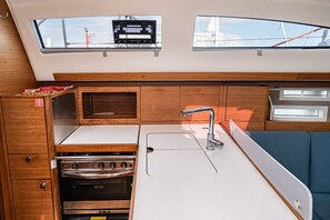A compact galley with a stove, sink, and storage cabinets, featuring a skylight and a view of the outside. - Sibenik Sun-soaked Sailing: A Luxurious Croatian Voyage (Pirovac)