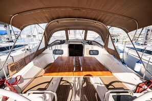 A boat deck with a central table, seating, and a view of other boats. - Sibenik Sun-soaked Sailing: A Luxurious Croatian Voyage (Pirovac)