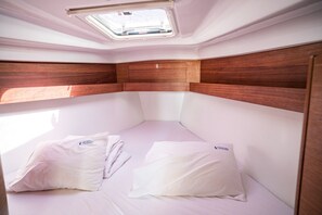 A compact, well-lit cabin with a skylight, a bed with pillows, and wooden paneling. - Sibenik Sun-soaked Sailing: A Luxurious Croatian Voyage (Pirovac)