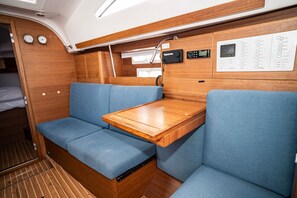 A compact interior with a wooden table, blue cushioned seating, and a control panel with a digital display. - Sibenik Sun-soaked Sailing: A Luxurious Croatian Voyage (Pirovac)