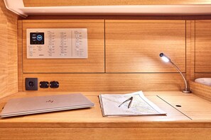 Een houten bureau met een laptop, een kaart, een pen, een bureaulamp en een thermostaat.