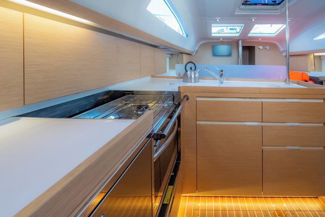 Een moderne keuken met een inbouwfornuis, houten kastjes en een klein eiland met een spoelbak.