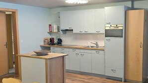 A compact kitchen with white cabinets, a wooden countertop, a sink, and a refrigerator. - Am Ryschbächli Appartement/Fewo, Dusche oder Bad, WC 6-Bettwohnung by Interhome (Zweisimmen)