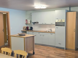 Eine kleine Küche mit weißen Schränken, einer Holz Arbeitsplatte, einem Spülbecken und einem Kühlschrank.
