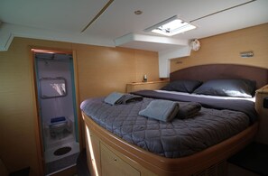 A compact bedroom with a bed, bedside table, and a skylight. - Sun-Kissed Sailing Adventure in Islas Sarónicas (Alimos)