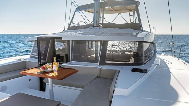 Un yate con zona de comedor que incluye mesa, cojines y vistas al mar.