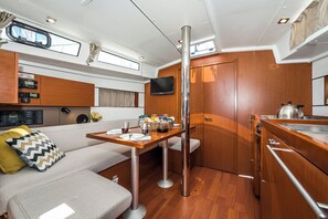 A compact kitchen with a dining area, a TV mounted on the wall, and a wooden cabinet. - Sun-Kissed Sailing Adventure in Zadar, Croatia (Biograd na moru)