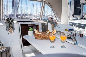A boat's deck with a table, a basket of bread, two glasses of orange juice, and a potted plant. - Sun-Kissed Sailing Adventure in Zadar, Croatia (Biograd na moru)
