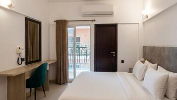 A hotel room with a bed, desk, chair, and a ceiling fan.