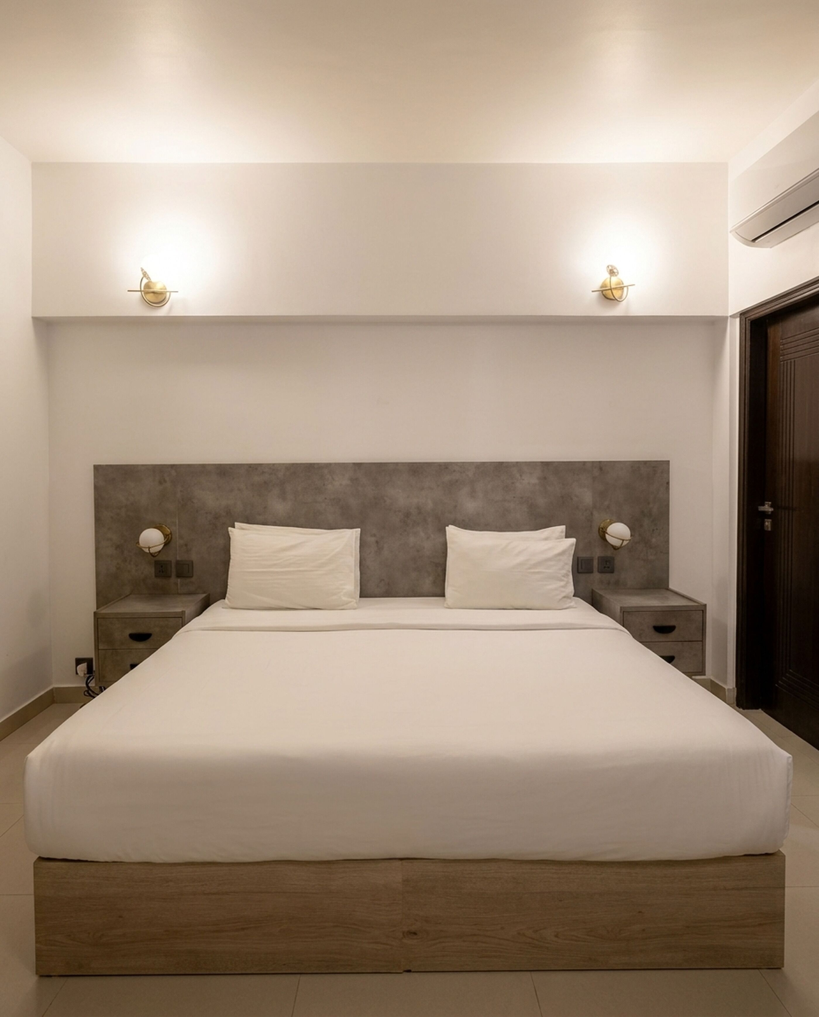A modern bedroom with a large bed, two bedside tables, and wall-mounted lighting.