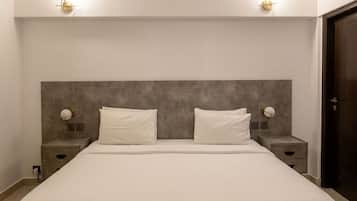 A modern bedroom with a large bed, two bedside tables, and wall-mounted lighting.