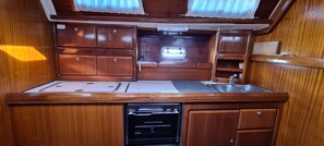 A compact kitchen with wooden cabinets, a sink, and a built-in stove.