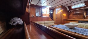 A cabin interior with a wooden bench, a cushioned seating area, and a table with a bowl. - Macedonian Sun and Beach Sailing Extravaganza from Kavala (Kavala)