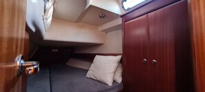 Une petite cabine comprenant un lit, un petit coin salon et une fenêtre.