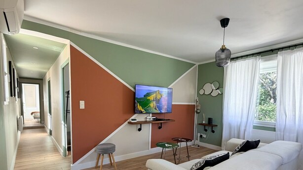 En moderne stue med sofa, fjernsyn og trappe op til et andet rum.