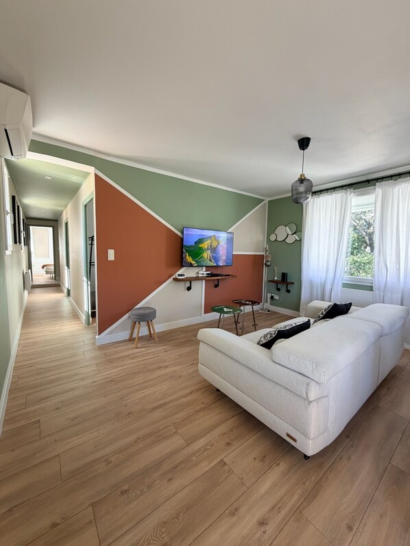 Ein modernes Wohnzimmer mit einer Couch, einem Fernseher und einer Treppe, die in einen anderen Raum führt.
