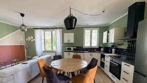 En kompakt opholdsstue med spiseplads, tekøkken og sofa.