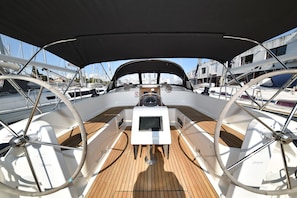 A sailboat deck with a steering wheel, a small screen, and a covered area. - Sun-Kissed Sailing Adventure in Zadar, Croatia (Zadar)