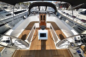 Ein Bootsdeck mit zentralem Steuer, einem kleinen Bildschirm und einem Holzboden.