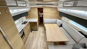 Ein kompaktes Wohnmobil-Interieur mit einer Küchenzeile, einem Essbereich und einer Sitzecke mit Blick.