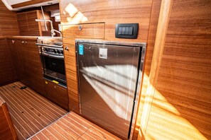 A compact kitchen with a stove, oven, and refrigerator, wooden paneling, and a small sink. - Sibenik Sun-soaked Sailing: A Luxurious Croatian Voyage (Pirovac)