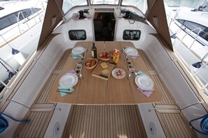 A boat deck with a dining table set for four, surrounded by chairs, and a central aisle. - Sibenik Sun-soaked Sailing: A Luxurious Croatian Voyage (Pirovac)