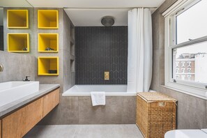 Ein modernes Badezimmer mit einer Badewanne, einem Fenster und gelben Ablageflächen.