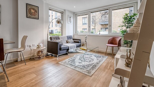 A modern living room with a sofa, coffee table, and a rug. - Modern Surrey Quays Flat (London)
