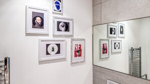 A wall with framed pictures and a mirror reflecting additional frames. - Modern Surrey Quays Flat (London)